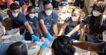 leadership-event-social.jpg students working in a group putting hands together in the center of a table wearing surgical masks